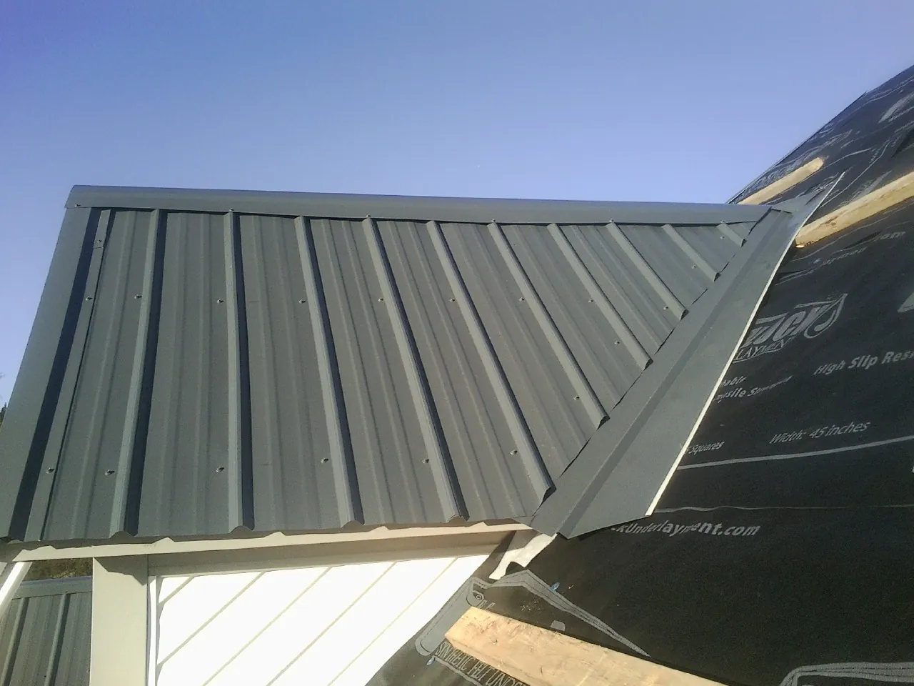 Gray metal roof panels going on over a garage gable in Leetsdale