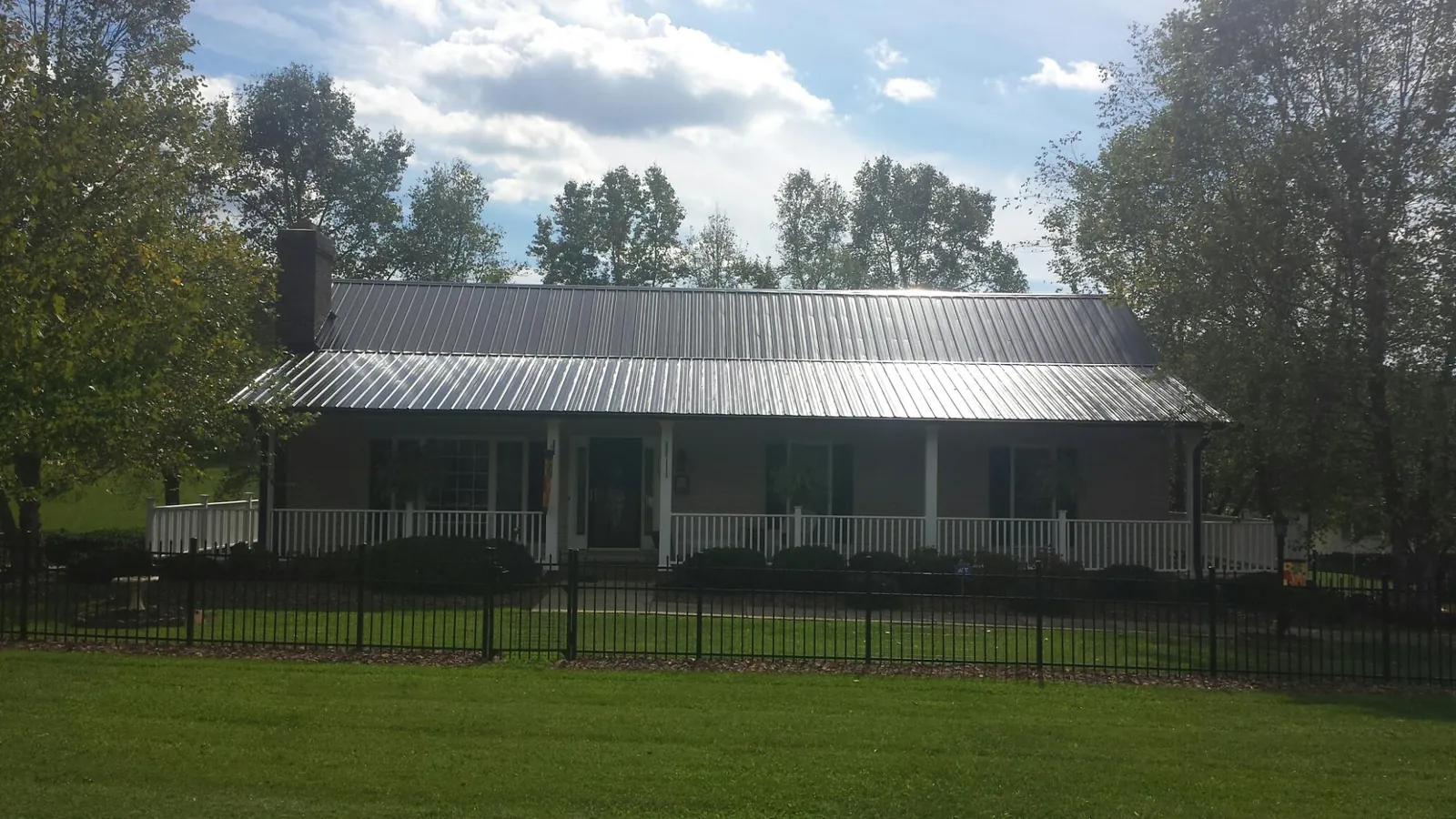 Gray metal roof on a brick ranch with a full width front porch — Gutter Guard Installation work by our crew in Leetsdale