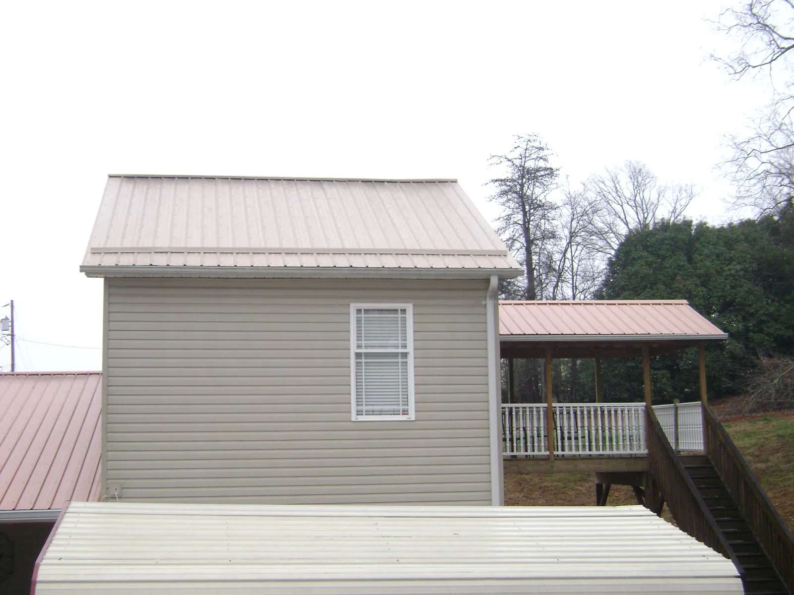 Tan metal roofs on a two story addition and attached porch, from a Roof Replacement job in Leetsdale