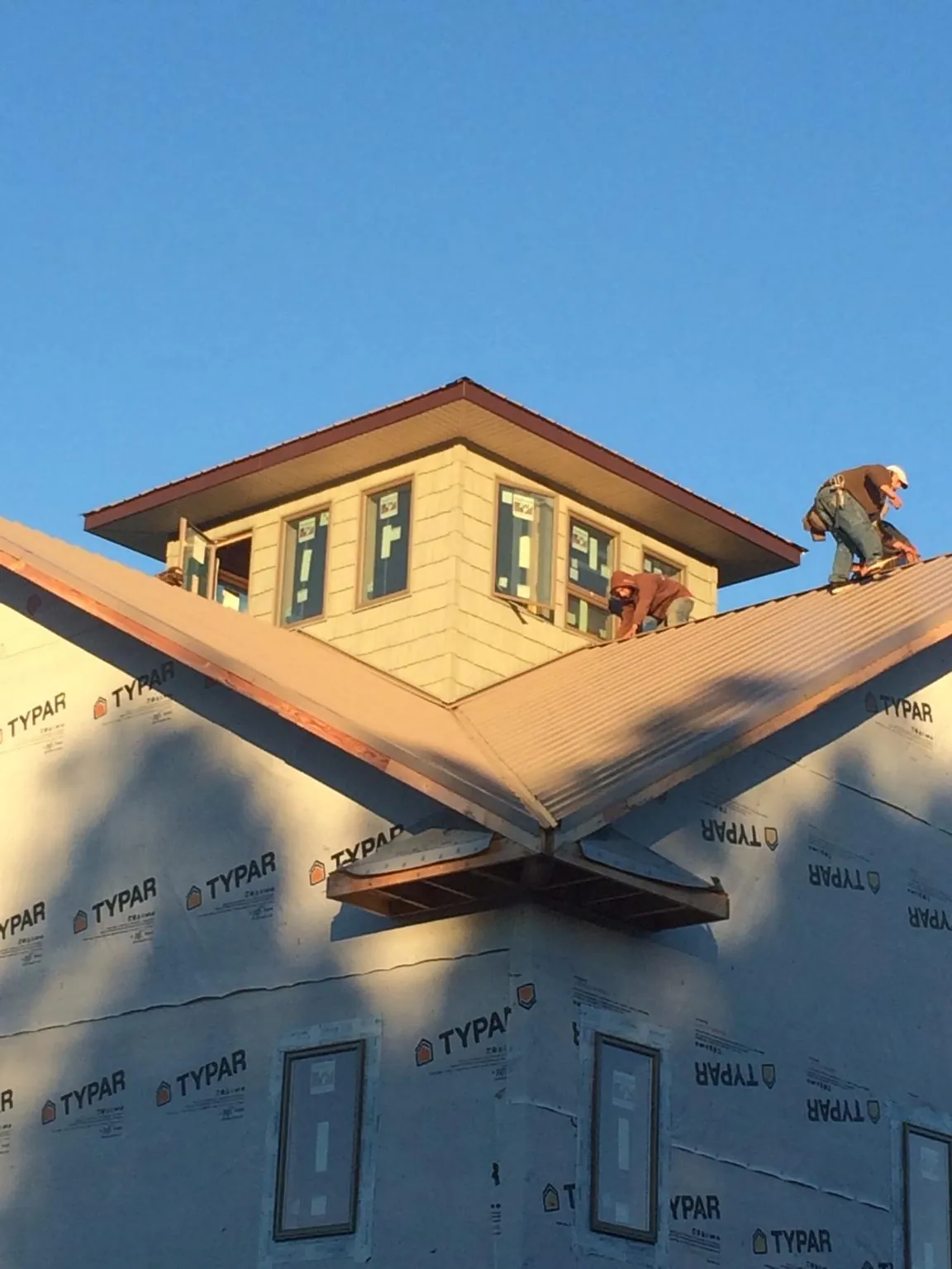 Roofers working around a rooftop cupola on a new metal roof at sunset — Roof Waterproofing in Leetsdale by Roofing Brothers